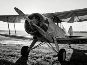 Historyczna fregata żaglowa płynąca po wzburzonym oceanie w blasku zachodzącego słońca.